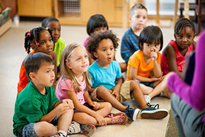 Children sitting on the floor listening to their teacher