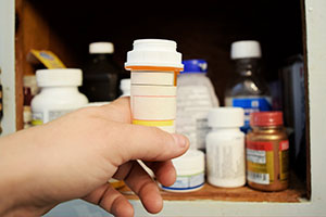 Child taking prescription bottle out of medicine cabinet