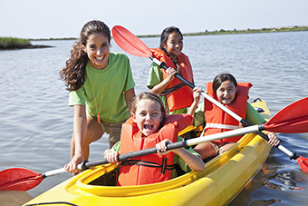 Girls kayaking with camp counselor