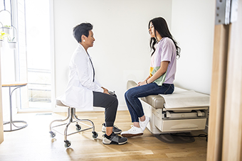 Doctor talking privately with a teen girl in an exam room