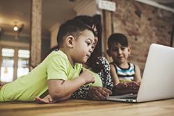 Two children looking at the computer with their mother.
