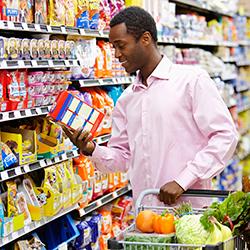 Man reading nutrition facts label on box at grocery store