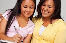 Teen girl writing with mom